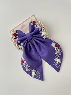 a purple bow with flowers and pearls on it