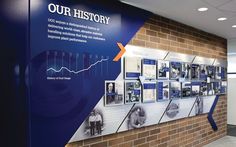 a brick wall with posters on it and people walking by in the hallway next to it