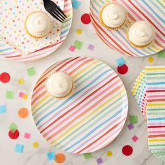 two plates with cupcakes on them next to confetti paper napkins