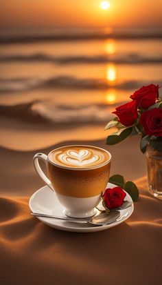 a cup of coffee on a saucer with red roses in front of the ocean