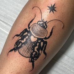 a black and white beetle tattoo on the right leg, with stars around its legs