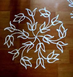 a wooden floor covered in white yarn with leaves drawn on the ground next to it