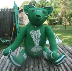 a green teddy bear sitting on top of a wooden table