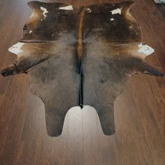 a brown and white cowhide rug sitting on top of a wooden floor