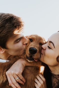 a man and woman kissing with a dog in front of the camera on a sunny day