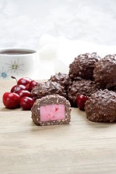 chocolate and cherries on a wooden table with a cup of coffee in the background