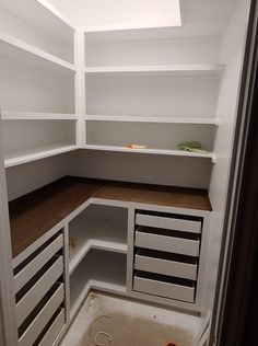 an empty pantry with white shelves and drawers