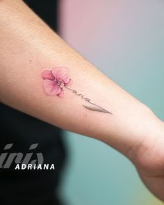 a woman's arm with a pink flower on it and a knife in the middle