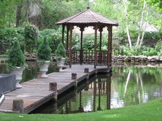 a gazebo sitting on top of a wooden pier next to a lake in a park