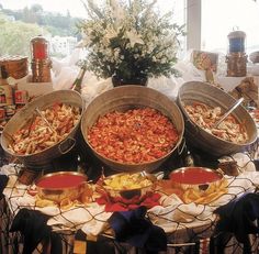 several buckets filled with food sitting on top of a table next to other foods