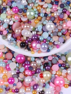 a white bowl filled with lots of different colored pearls