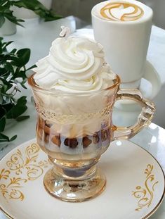 there is a cup with whipped cream in it on the plate next to two cups