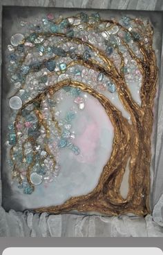 a painting in a box with gold foil and glass beads on the tree's branches