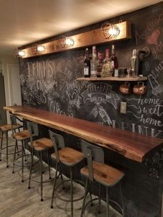 a long bar with lots of chalk writing on the wall and wooden barstools