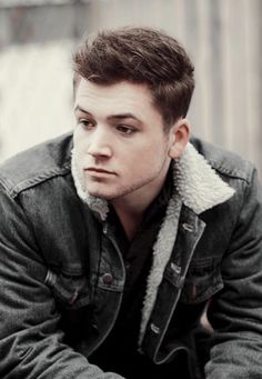 a young man is sitting down with his hands on his knees and looking at the camera