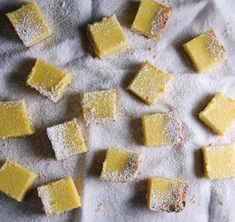 small squares of yellow cake sitting on top of a white cloth covered in powdered sugar