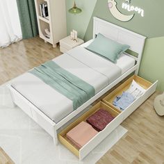 a bed with two drawers underneath it in a room that has hardwood floors and green walls