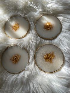 four white plates with gold flecks on them sitting on a fur covered surface