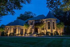 a large house lit up at night with lights on it's windows and landscaping