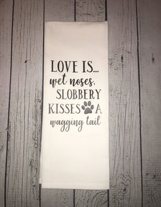 a tea towel with the words love is wet noses, slobberry kisses a wagging tail on it