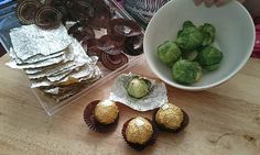 some chocolates are sitting on a table next to a bowl of brussels sprouts