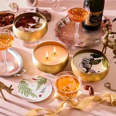 a table topped with wine glasses and plates filled with food next to candlelight candles