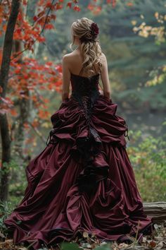 a woman in a red dress is walking through the woods with her back to the camera