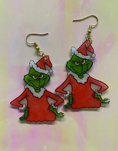 two green cartoon characters wearing santa hats and holding hands in front of a pink background