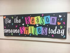 a colorful sign that says be the reason someone smiles today on it's wall