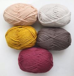 four balls of yarn sitting next to each other on a white surface with one ball in the middle