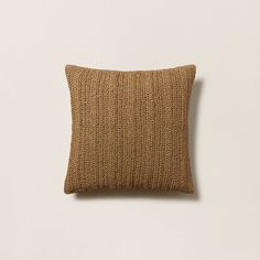 a brown knitted pillow on a white wall