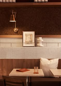 a table and chairs in a room with white tile on the wall, brown wood paneling