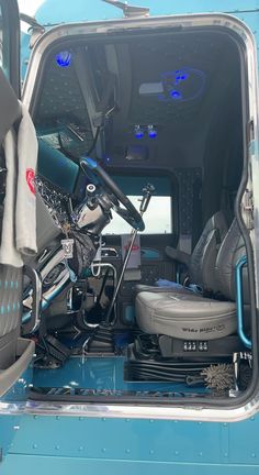 the inside of a blue truck with its door open and seats folded up in front