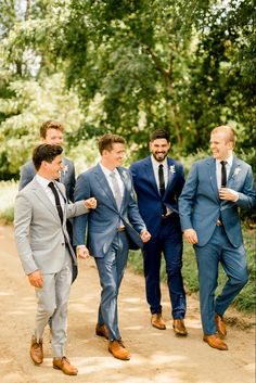 a group of men in suits walking down a dirt road