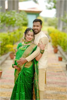 a man and woman posing for the camera in green sarees with their arms around each other