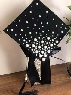 a graduation cap decorated with pearls and tassels on top of a wooden table