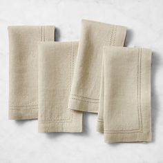 three linen napkins with white stitching on them