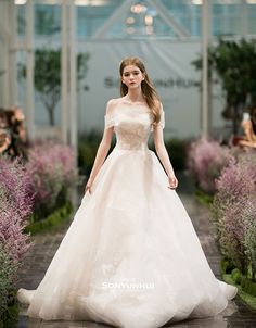 a woman in a wedding dress walking down a runway