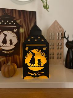 a lighted lantern sitting on top of a table next to two pictures and pumpkins