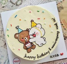 a happy birthday cake with a teddy bear holding a party hat