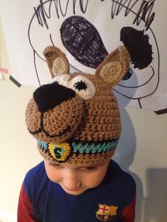 a young boy wearing a crocheted hat with ears and nose, made to look like a dog