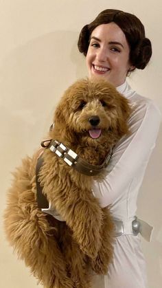 a woman holding a furry dog in her arms and wearing a star wars costume on it's chest