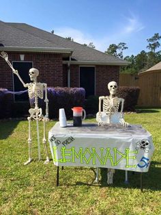 two skeletons are sitting at a table outside