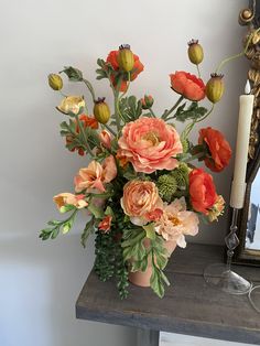 a vase filled with flowers sitting on top of a wooden table next to a candle