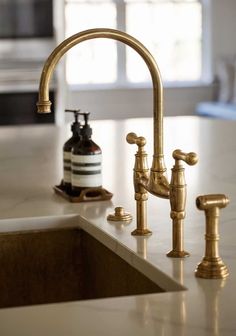 a kitchen sink with two faucets and soap dispenser on the counter