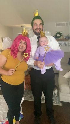 a man and woman dressed up as the little mermaid with pink hair holding a baby