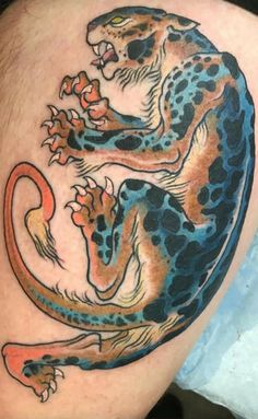 a tattoo on the leg of a man with a blue and orange dragon design on it