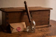 an old fashioned ink pen sitting on top of a wooden desk next to a envelope