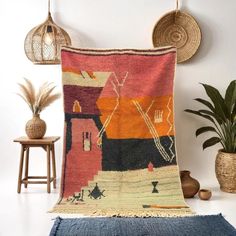 a colorful rug is hanging on the wall next to a potted plant