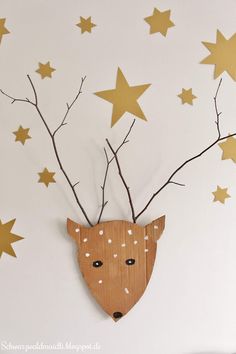 a wooden deer head with branches and stars on the wall in front of white background